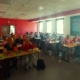 People voting in a classroom with red, orange or green cards,